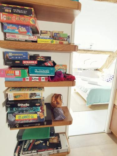 a stack of books on a shelf next to a bed at Villa spacieuse près de Senonches avec piscine privée in Tardais