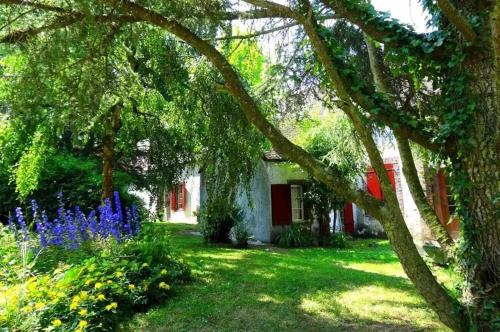 a house with a yard with blue flowers and trees at Villa spacieuse près de Senonches avec piscine privée in Tardais