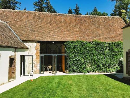 an external view of a house with a green hedge at Villa spacieuse près de Senonches avec piscine privée in Tardais