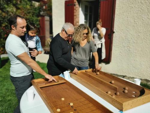 a group of people standing around a ping pong table at Villa spacieuse près de Senonches avec piscine privée in Tardais