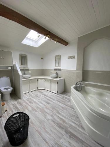 La grande salle de bains est pourvue d'une grande baignoire et de toilettes. dans l'établissement Maison familiale spacieuse à Niort avec jardin, à Niort