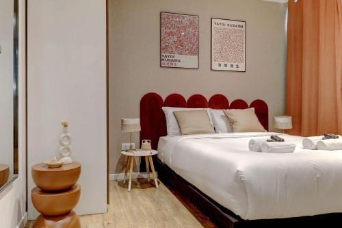 une chambre avec un grand lit avec une tête de lit rouge dans l'établissement Charme Parisien pres des Buttes-Chaumont, à Paris