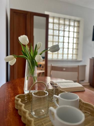 a table with a vase with white flowers in it at Agapella Apartamemty- Villa Agapella 250m from the beach in Sopot