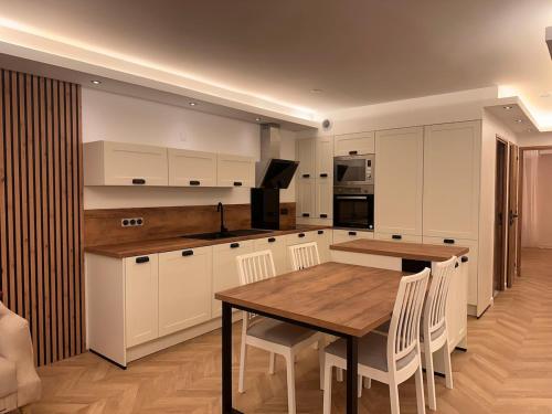 une cuisine avec une table en bois et des armoires blanches dans l'établissement Appartement La Baule, à La Baule