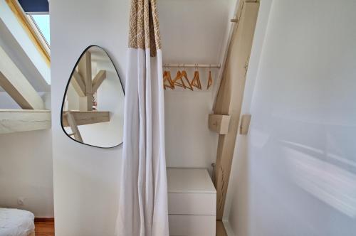 a bedroom with a mirror and a white curtain at La grande porte du Baron in Nevers