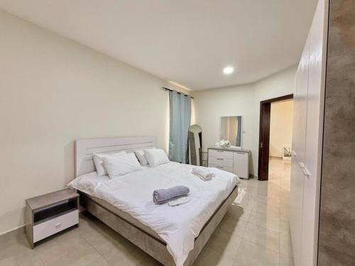 a bedroom with a large white bed with white sheets at Welcome to cozy one bedroom in Abu Dhabi