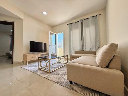 a living room with a couch and a tv at Welcome to cozy one bedroom in Abu Dhabi
