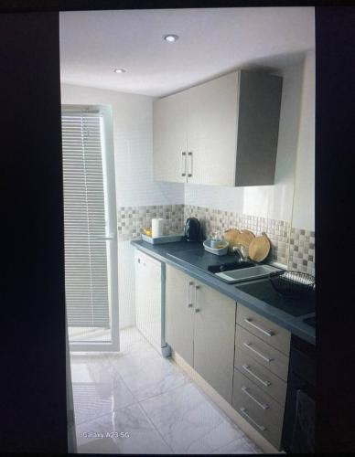 a kitchen with white cabinets and a black counter top at Apartamento Alicia in Daimuz
