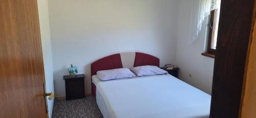 a bedroom with a bed with a red and white headboard at Diverso in Zelenika