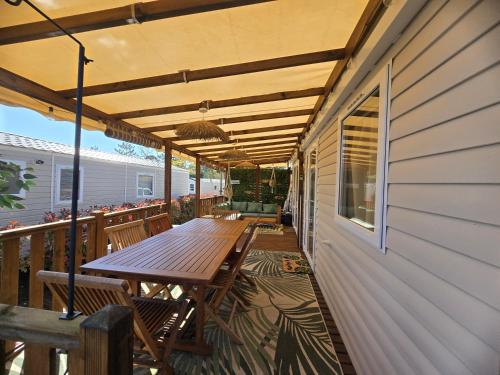patio z drewnianym stołem i ławkami na pokładzie w obiekcie Mobil home tout confort au Camping Les Viviers, Cap Ferret w mieście Claouey
