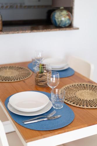 einen Tisch mit Tellern und Gläsern auf einem Holztisch in der Unterkunft Apartment Seaview Port Cambrils in Cambrils