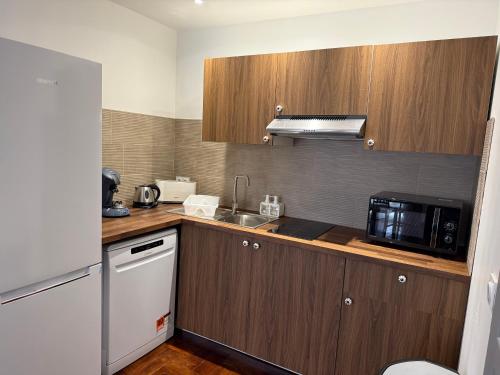 a kitchen with wooden cabinets and a sink and a microwave at Domaine Le Rocher d Argent avec Piscine Extérieur ,Jacuzzi Intérieur et Salle de jeux in Berre-les Alpes