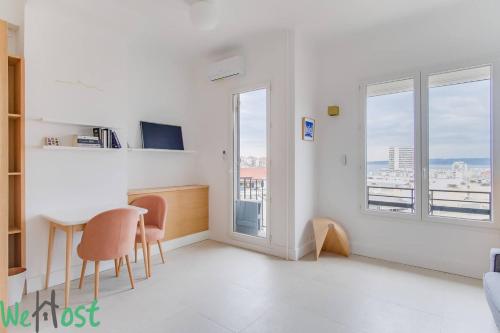 Cette chambre blanche dispose d'une table, de chaises et de fenêtres. dans l'établissement Endoume 3 - Marseille, à Marseille