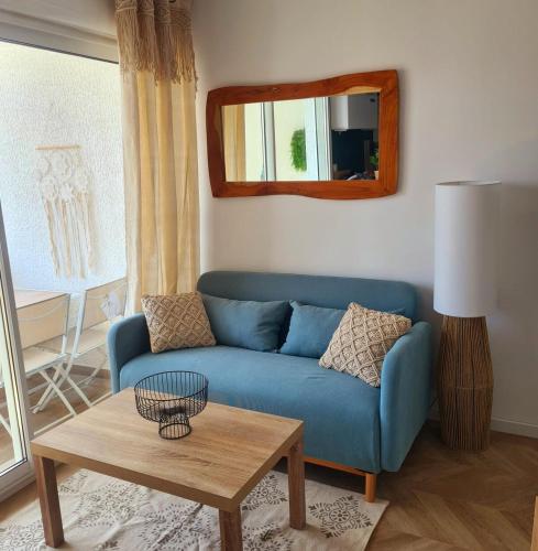 un salon avec un canapé bleu et une table dans l'établissement Appartement sur le Port de Meze, à Mèze