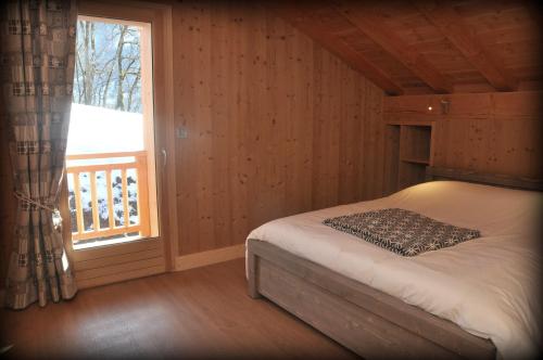 a bedroom with a bed next to a window at Chalet Le Villard Samoens in Samoëns