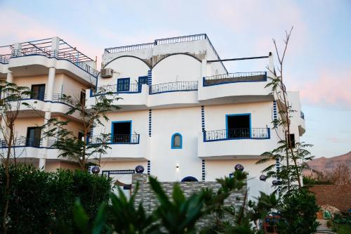 a white building with balconies and trees at Sharqotel Luxor in Luxor