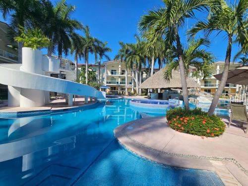 a swimming pool with palm trees and a resort at Diamante Lakes Condominium, in front of Arena GNP in Acapulco