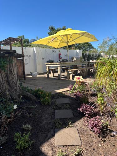 a patio with a picnic table and an umbrella at Greyton Toad Hall exclusive use up to 18 and by supplement up to 22 with massive pool and hot tub and sometimes we rent individual rooms in Greyton