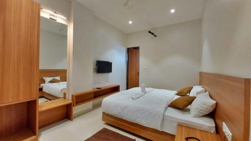 a bedroom with two beds and a mirror at Coco Resort and Banquet in Pune