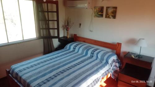 a bedroom with a bed with a blue and white striped blanket at Posada del Arroyo in Las Rabonas