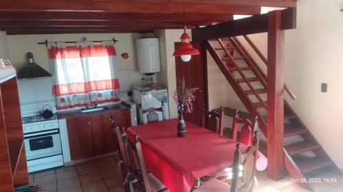a kitchen with a red table and a kitchen with a staircase at Posada del Arroyo in Las Rabonas