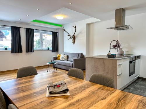 a kitchen and living room with a wooden table in a room at Ours Living Larmkogel - inkl Sauna in Hollersbach im Pinzgau