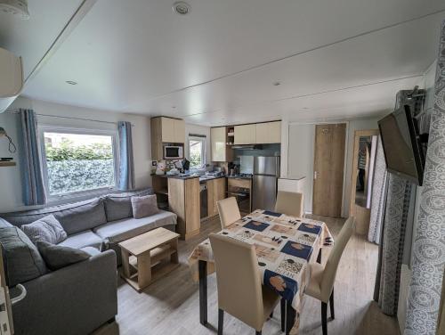 a living room and kitchen with a table and a couch at Mobil home climatisé récent 2 salles d'eau, 2 WC à SIBLU Bonne Anse plage in Les Mathes