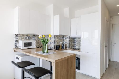 une cuisine avec des placards blancs et un vase de fleurs sur un comptoir dans l'établissement Sea View - Lovely Studio Promenade des Anglais, à Nice