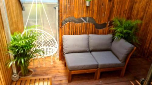 un canapé assis sur un porche avec deux plantes dans l'établissement Terrasse, à Toulouse