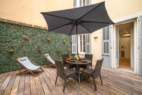 une table avec des chaises et un parasol sur une terrasse dans l'établissement Charme Niçois avec terrasse en ville, à Nice