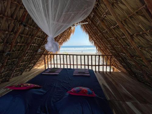 a bed in a straw hut with a view of the ocean at Bokanito Sam Chak in Boca del cielo