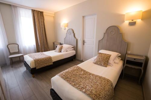 a hotel room with two beds and a window at Hotel Le Lion D'Or et Restaurant La Table Du Lion in Bayeux