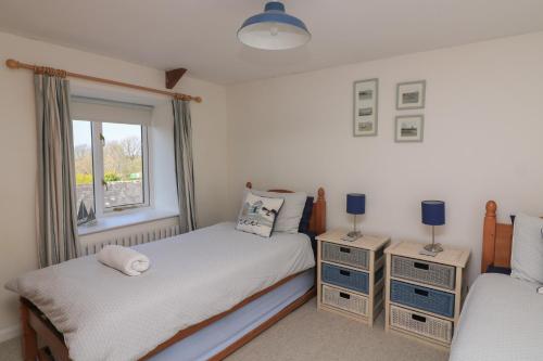 ein Schlafzimmer mit zwei Einzelbetten und einem Fenster in der Unterkunft Tinkers Cottage in Kingsbridge