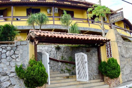 a yellow building with a gate and a stone wall at Atobás in Arraial do Cabo