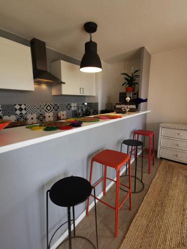 une cuisine avec trois tabourets rouges à un comptoir dans l'établissement Chez Sab, à Saint-Fons