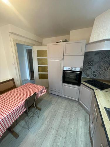 une cuisine avec des armoires blanches, une table et une cuisinière dans l'établissement Large Apartment Free Parking Mulhouse, à Mulhouse