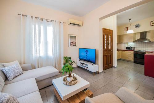 uma sala de estar com um sofá e uma TV em Aurum Syros em Hermópolis
