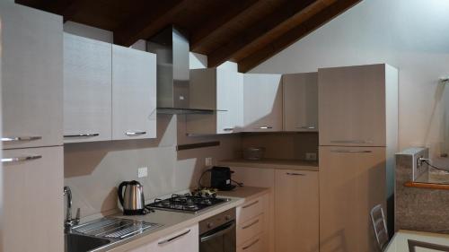 a kitchen with white cabinets and a stove top oven at Ciceri Properties Sandrin in Mergozzo