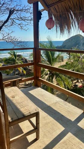 a wooden porch with a chair and a view of the beach at Lo Cósmico in Zipolite