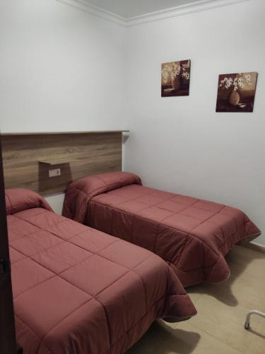 two beds in a hotel room with red sheets at Vivienda Rural Casa Ana in Prado del Rey