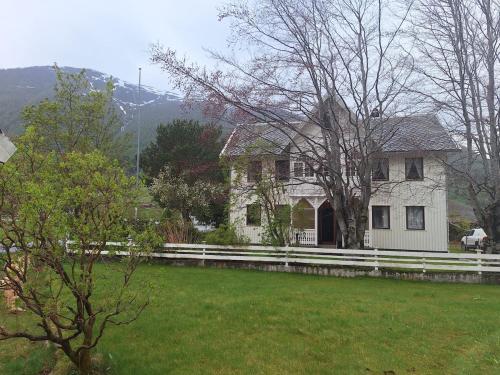 a white house with a fence in a field at Villa ved sjøen og fjellene in Myklebostad