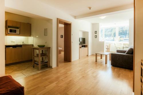 a living room with a couch and a kitchen at Panorama Spa Lodges DasSchiller MEDIUM in Bad Gastein