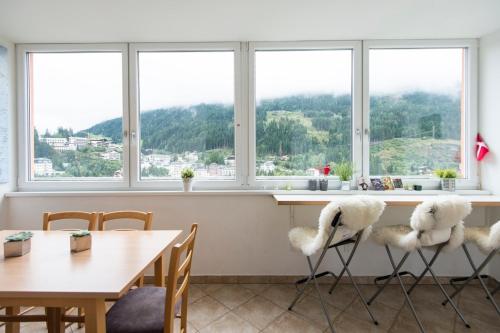 a dining room with a table and chairs and windows at Panorama Spa Lodges DasSchiller MEDIUM in Bad Gastein