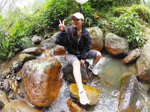 a woman sitting on rocks in a stream at Refugio Los Naranjales in El Colegio
