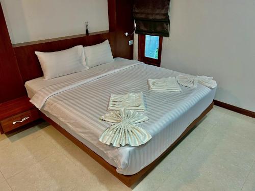 a large bed with white sheets and towels on it at บ้านสวนวารินทร์ in Ban Na Nian