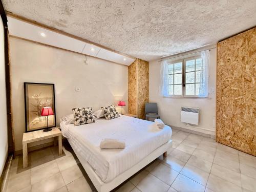 une chambre avec un grand lit blanc et une fenêtre dans l'établissement Paisible - Vue Mer - Jardin, à Carqueiranne