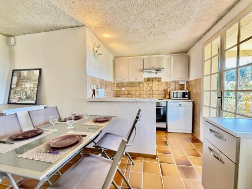 une cuisine avec une table et des chaises et une cuisine avec des armoires blanches dans l'établissement Paisible - Vue Mer - Jardin, à Carqueiranne