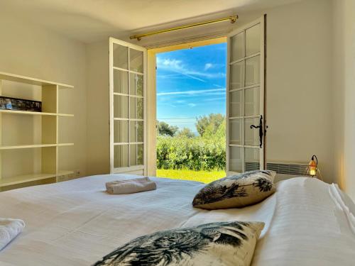 une chambre avec un grand lit avec une grande fenêtre dans l'établissement Paisible - Vue Mer - Jardin, à Carqueiranne