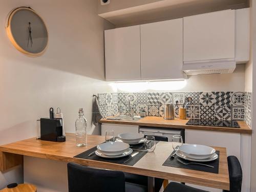 une cuisine avec une table et une horloge au mur dans l'établissement Studio cosy Villefranche-Sur-Saône, à Villefranche-sur-Saône