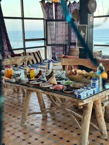 a picnic table with food on it with the ocean in the background at Imsouane petitsurfer SurfCamp in Imsouane